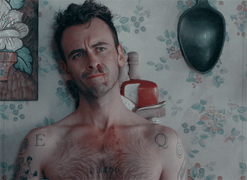 A gif of the character cassidy from preacher, he's shirtless and his nose is bleeding. he is smiling.